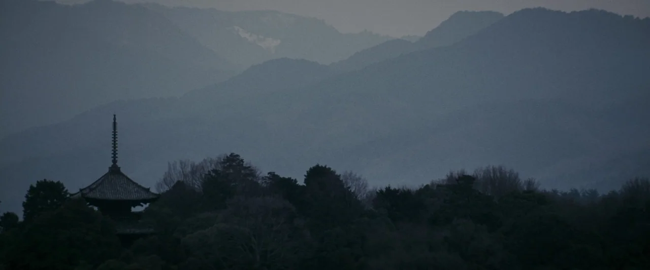 Memoirs of a Geisha (2005) movie still: establishing — Silhouetted layers of misty mountains stretch across the horizon under an overcast sky. A…
