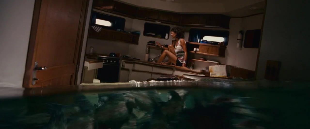 Piranha 3D (2010) movie still: wide — A flooded yacht interior features a woman perched on a counter away from water. The cabin is half-submerged…