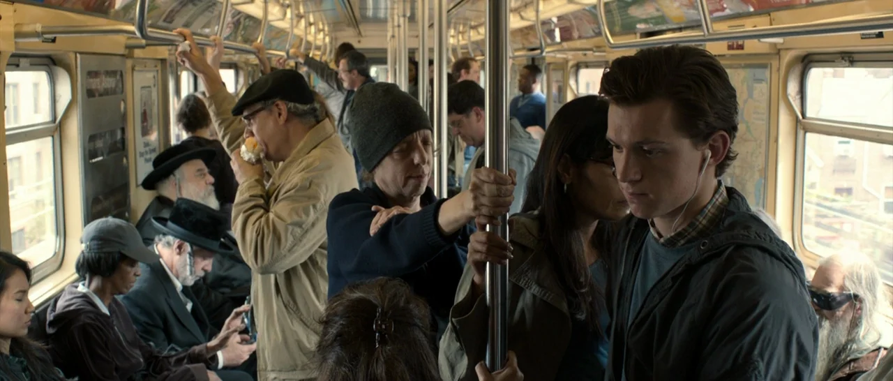 Spider Man: Homecoming (2017) movie still: medium — A crowded subway car interior filled with diverse passengers during the daytime. A young man…