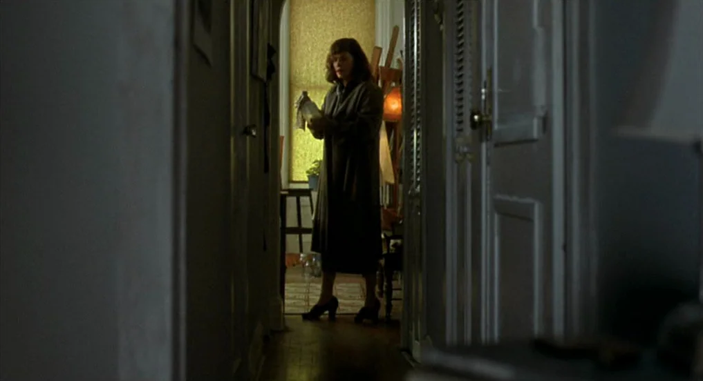 Pollock (2000) movie still: fullbody — A narrow residential hallway leads toward a bright window at the far end. A woman stands in the doorway…