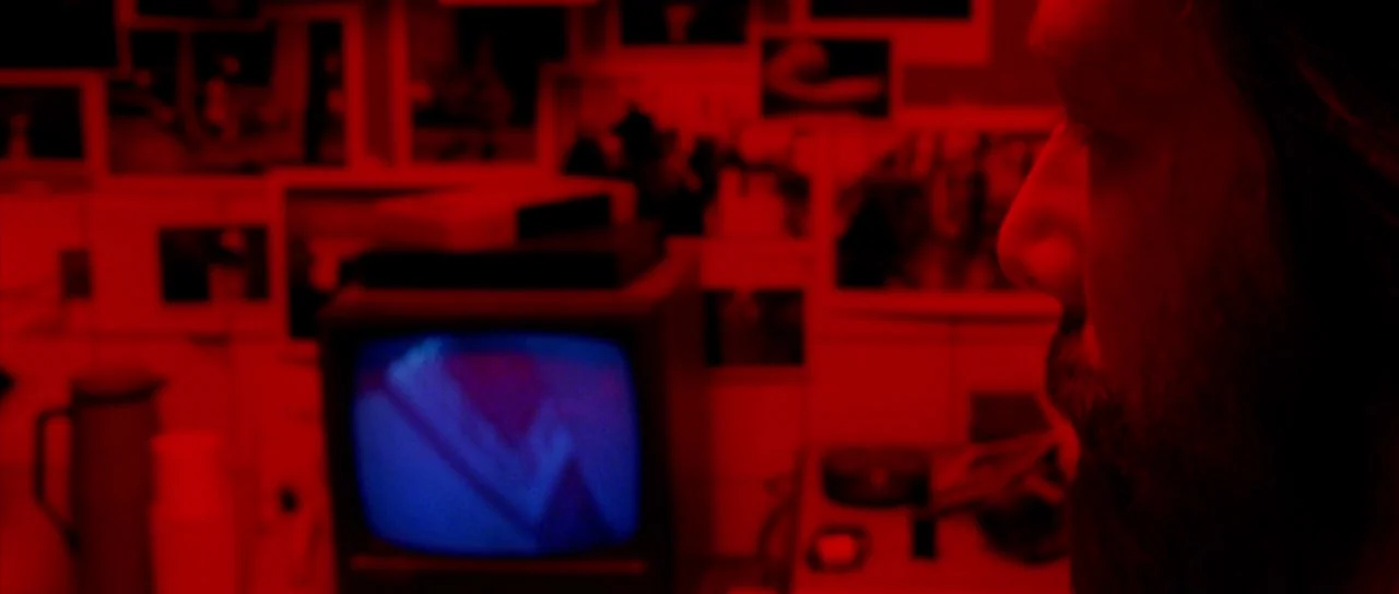 The Strange Colour of Your Body’s Tears (2013) movie still: closeup — A darkroom space is filled with numerous photographs pinned against a wall. A…