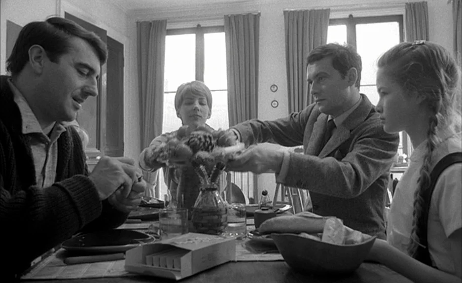 Le Feu Follet (1963) movie still: medium — A group of four adults and a teenager gather at a table during lunch. They share a bowl of food while…