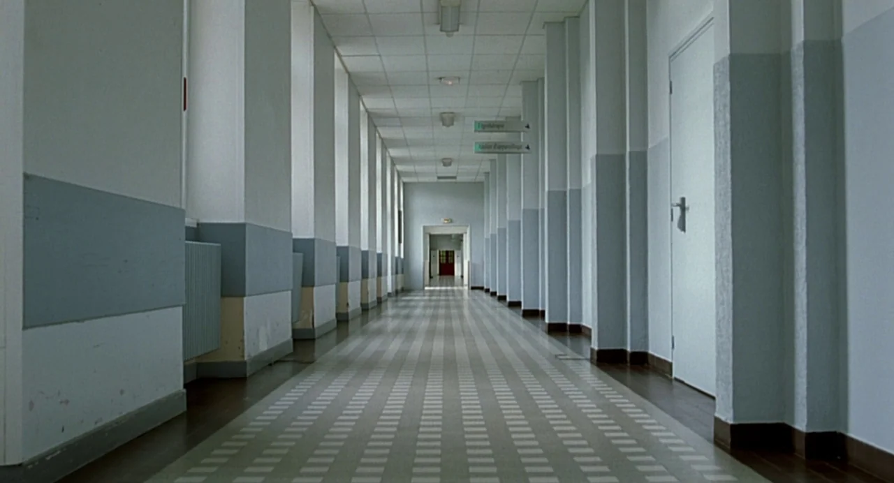 The Diving Bell and the Butterfly (2007) movie still: establishing — A long, symmetrical hospital hallway features white pillars and light blue…