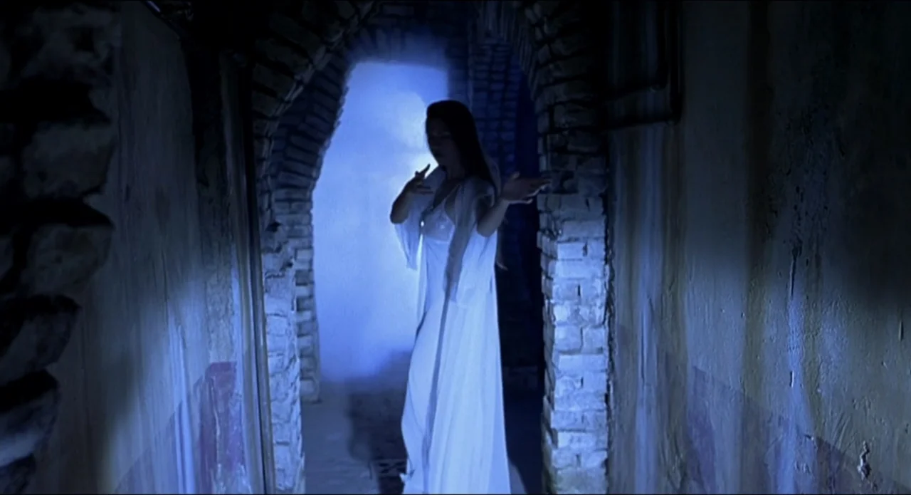Scary Movie 2 (2001) movie still: fullbody — A narrow stone archway filled with dense blue fog sits between two brick walls. A woman in a white gown…