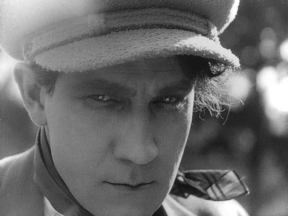 Coeur Fidele (1923) movie still: closeup — A close-up shot focusing on the head and shoulders of a man wearing a cap. He stares directly ahead into…