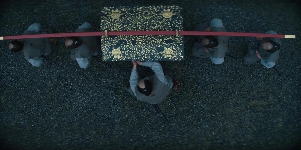 Shogun (2024) movie still: wide — Five men in traditional Japanese attire kneel on a patch of loose gravel ground. A large decorative chest…
