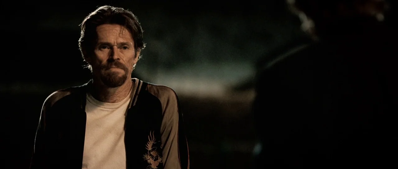 Daybreakers (2009) movie still: medium — A man stands in a dark, outdoor space at night with indistinct shadows behind him. He wears a satin jacket…