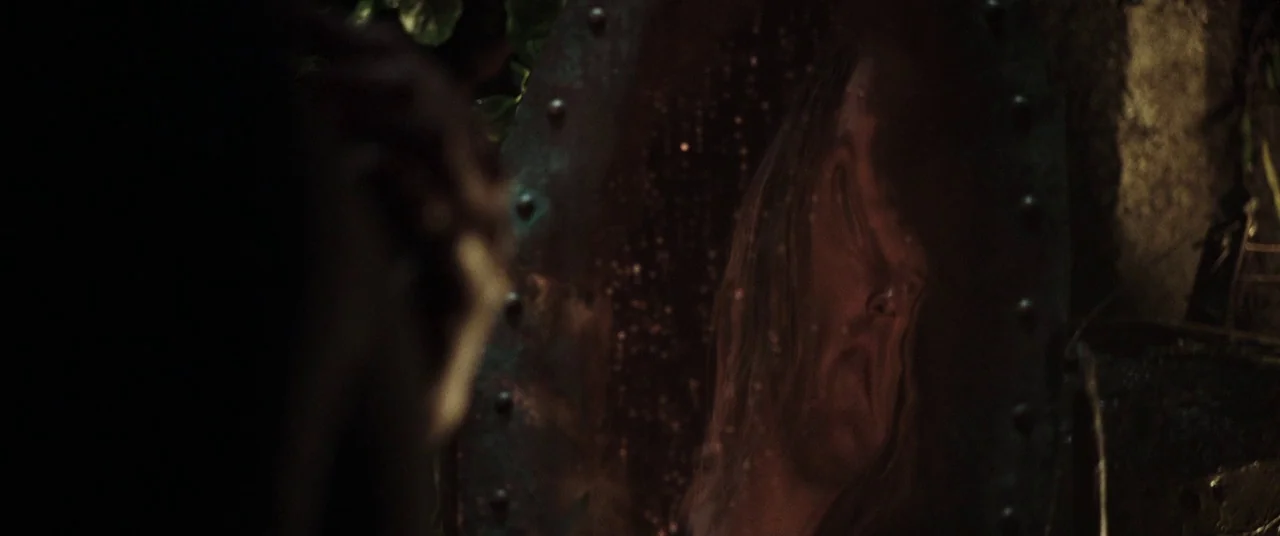 Alien: Covenant (2017) movie still: closeup — A dimly lit, narrow bathroom space contains a circular, riveted metal-framed wall mirror. A person…