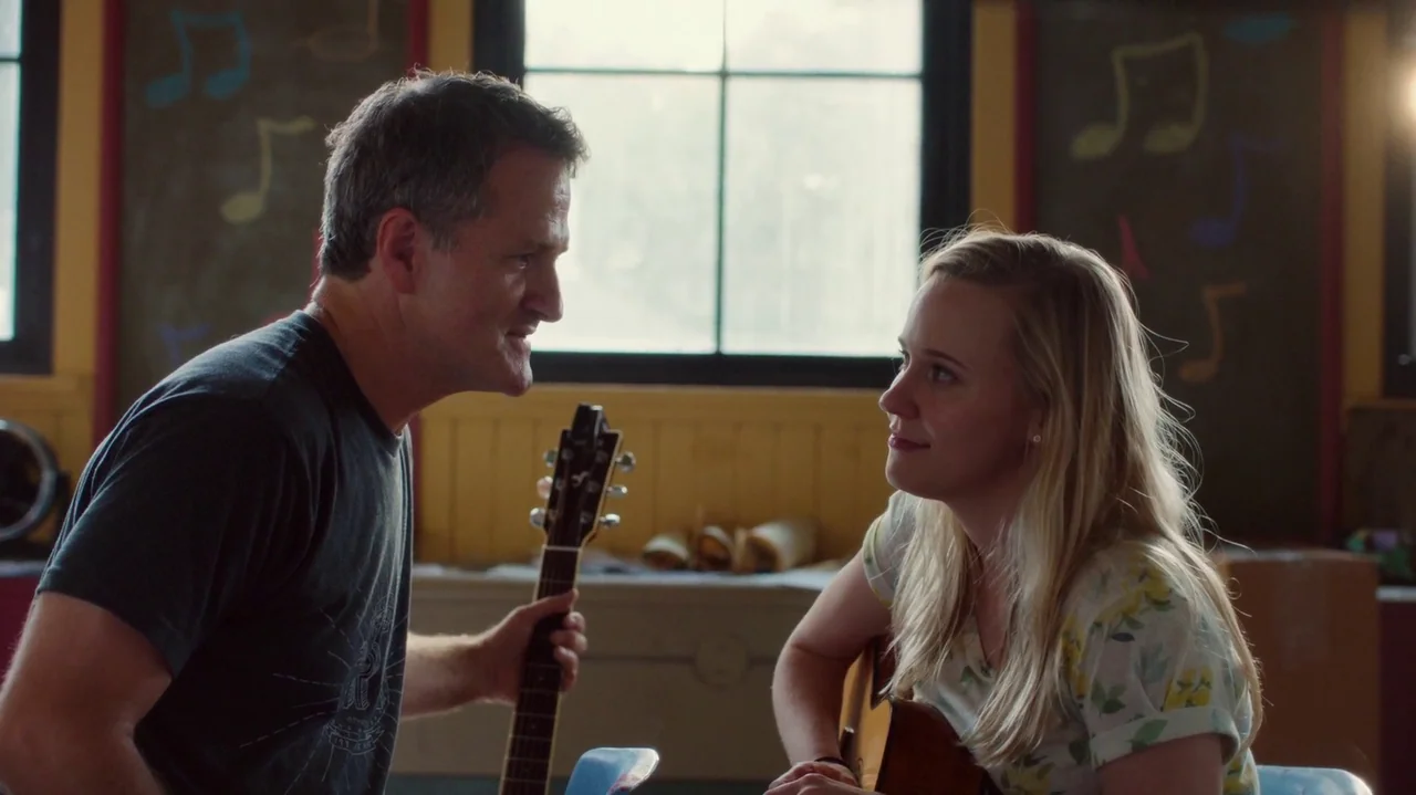 Saint Frances (2019) movie still: medium — A room with yellow wood paneled walls and chalkboards decorated with colorful musical note drawings. A…