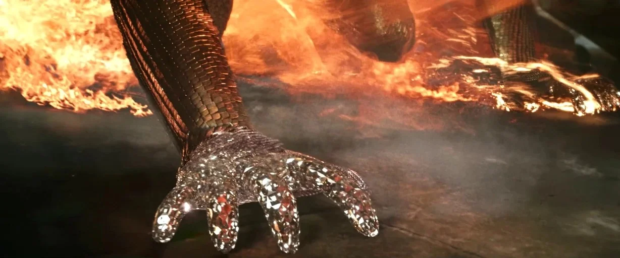 X-men (2000) movie still: closeup — A dark ground surface is engulfed in bright orange flames near a metallic object. A faceted crystalline…