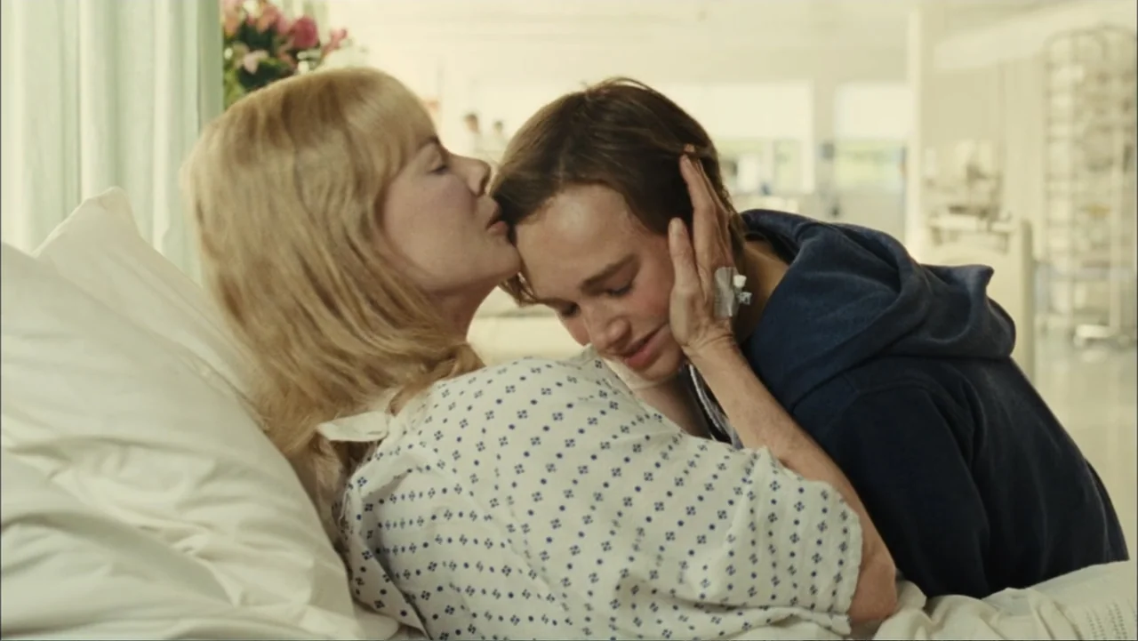 Before I Go to Sleep (2014) movie still: medium — A sterile hospital room contains a bed with a patient and a visitor. A woman in a hospital gown…