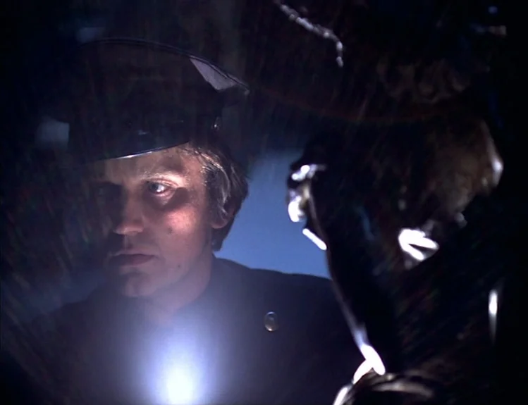 The Arrival of Joachim Stiller (1976) movie still: closeup — A dark, shadowy interior setting is illuminated only by a small, intense flashlight…