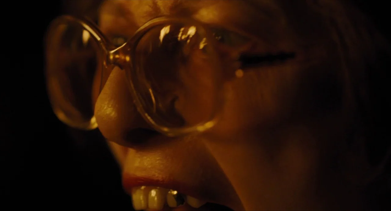 Snowpiercer (2013) movie still: closeup — The frame shows a dark, indeterminate space illuminated by a warm, concentrated light source. An elderly…