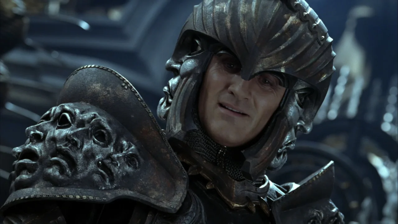 The Chronicles of Riddick (2004) movie still: closeup — A man in ornate fantasy armor stands in a dark, metallic interior setting. He wears a…