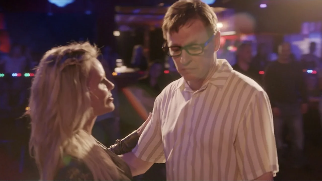 Ask Me to Dance (2022) movie still: medium — A crowded nightlife venue features low lighting with blurred neon background elements. A man and a…