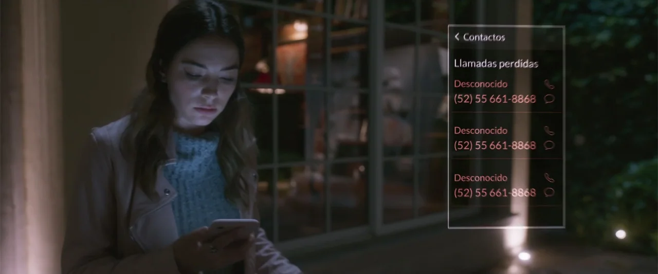 Crazy for Change (2020) movie still: medium — A woman stands on a dimly lit patio at night in front of a window. She holds a mobile phone, looking…