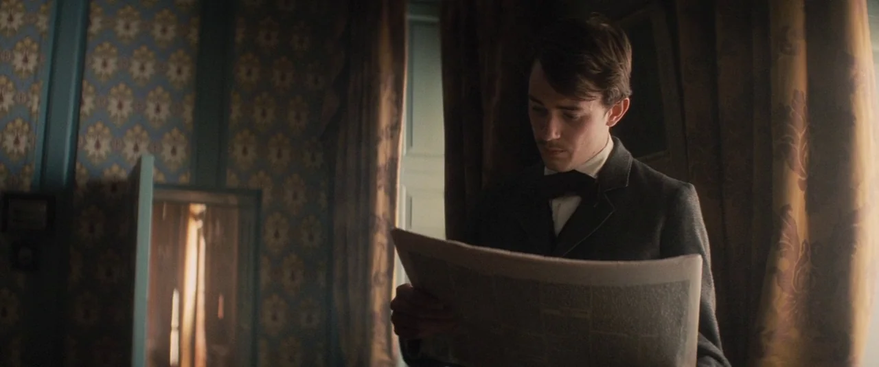 The Invisible Woman (2013) movie still: medium — A study features intricate patterned blue and gold wallpaper next to heavy bronze curtains. A young…