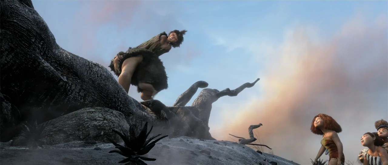 The Croods (2013) movie still: fullbody — A rocky landscape features a large, gnarled dead tree under a soft sky. A character crouches high on the…