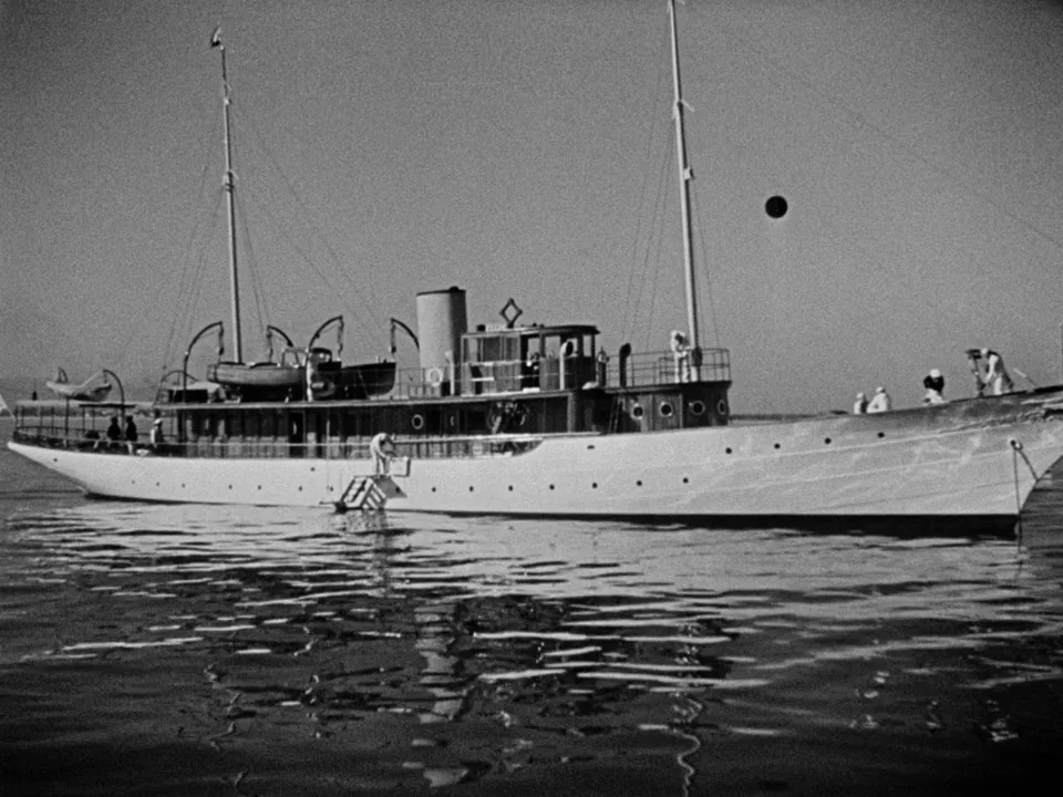 It Happened One Night (1934) movie still: wide — A vintage motor yacht floats on calm, open water under a clear sky. Several figures in…