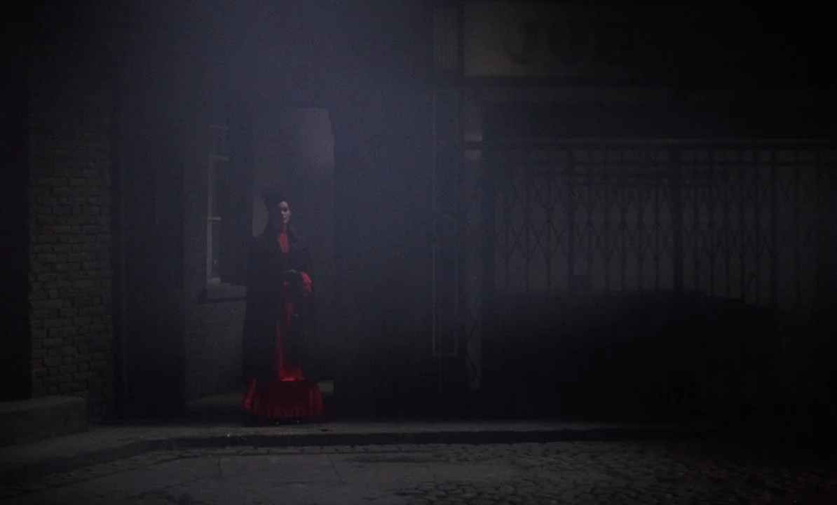 Dr Jekyll & Sister Hyde (1971) movie still: wide — A dark, foggy urban street at night with cobblestone ground and a brick wall. A lone woman…