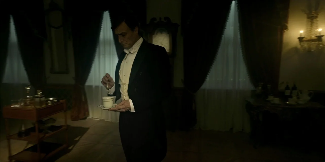 Oslo (2021) movie still: medium — A dark, wood-paneled room is furnished with heavy curtains and a grandfather clock. A man in formal evening wear…