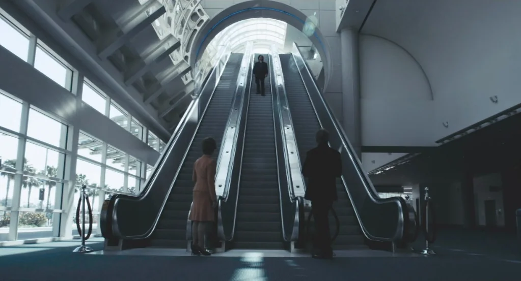 My Son, My Son, What Have Ye Done? (2009) movie still: wide — A spacious convention center atrium features a central escalator illuminated by a…