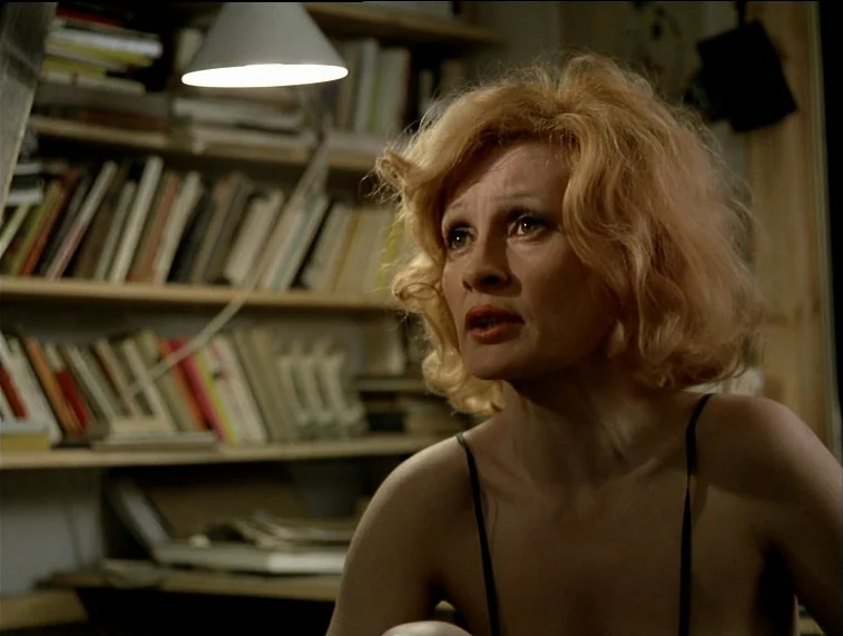 Mother Kusters Goes To Heaven (1975) movie still: medium — A residential room features wooden shelves densely packed with rows of books. A blonde…