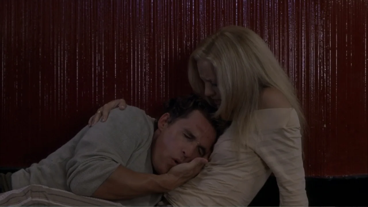 How to Lose a Guy in 10 Days (2003) movie still: medium — Two individuals sit on the floor in front of a textured red wall. The man leans his head…