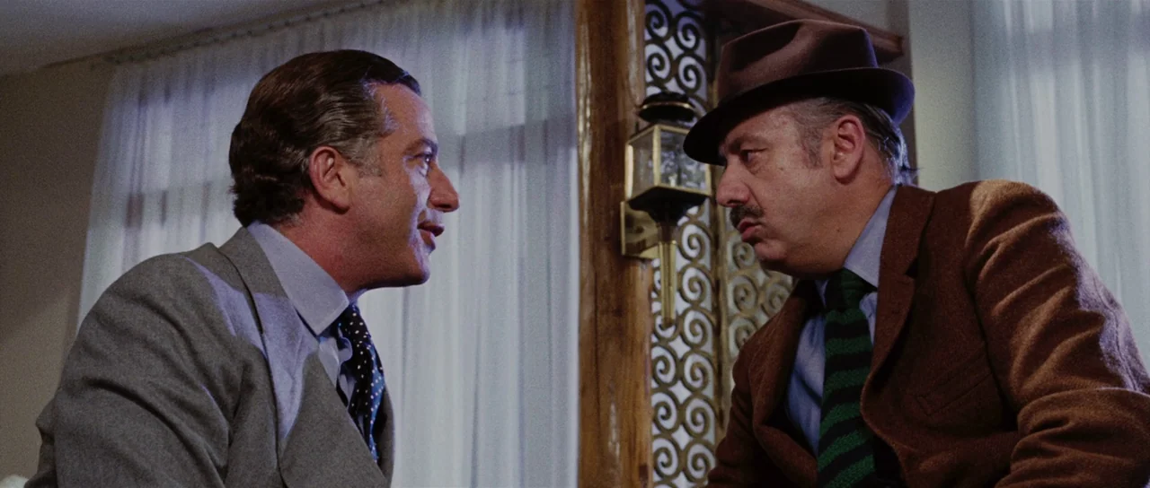 Death Walks On High Heels (1971) movie still: medium — A residential room features sheer white curtains and an ornate gold metal wall fixture. Two…