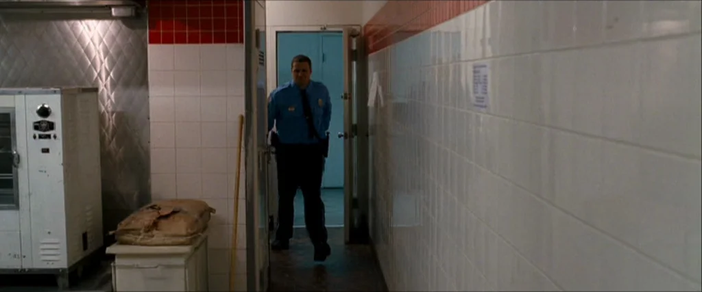 Observe And Report (2009) movie still: fullbody — A service corridor with white ceramic wall tiles and a red tiled trim detail. A security guard…