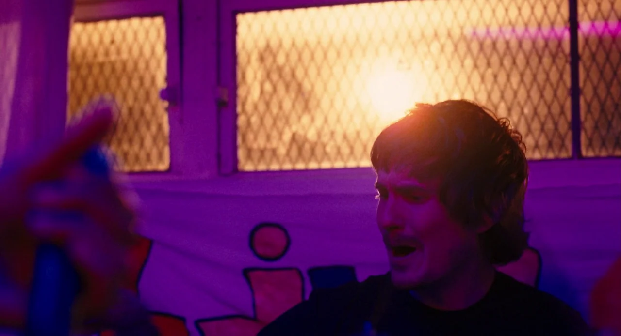 Pariah (2011) movie still: medium — A dimly lit club interior features a window with a metal security grid. A man stands in the foreground, his face…