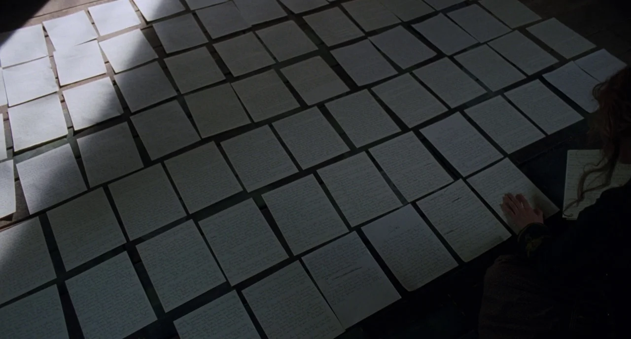 Little Women (2019) movie still: medium — A wooden floor is covered in dozens of handwritten papers arranged in a grid. A person with auburn hair…