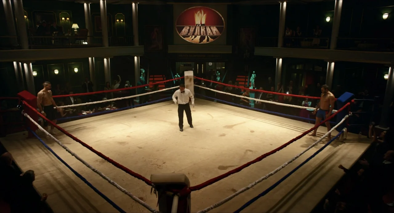 Boyka: Undisputed IV (2016) movie still: wide — An indoor venue centers a lit square canvas stage surrounded by audience seating balconies. Two…