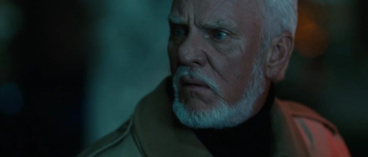 Halloween (2007) movie still: closeup — An older man stands on a dark street at night under neon illumination. He gazes off-camera with a fixed,…