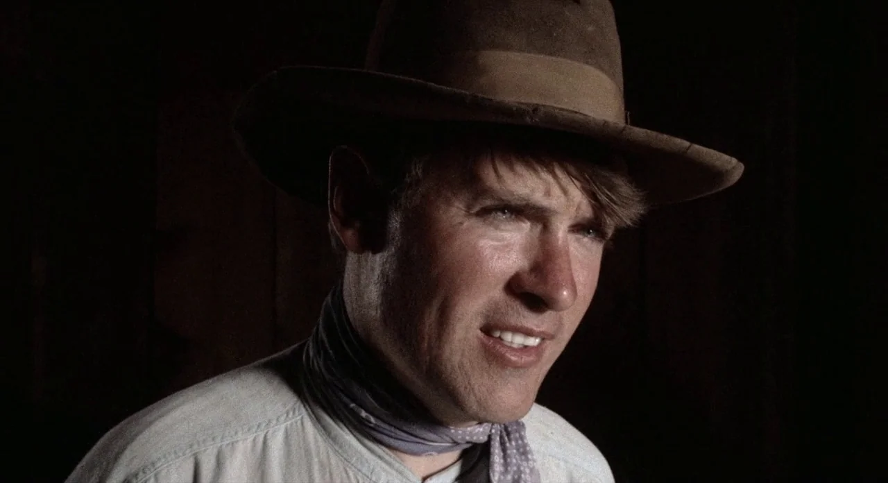 The Shooting (1966) movie still: closeup — A dark wooden interior serves as the background for a man's portrait. The man wears a brown fedora and…