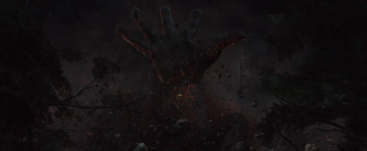 The Cabin In The Woods (2012) movie still: closeup — A dark rocky surface is fractured by an emerging giant hand made of stone. The hand pulses with…
