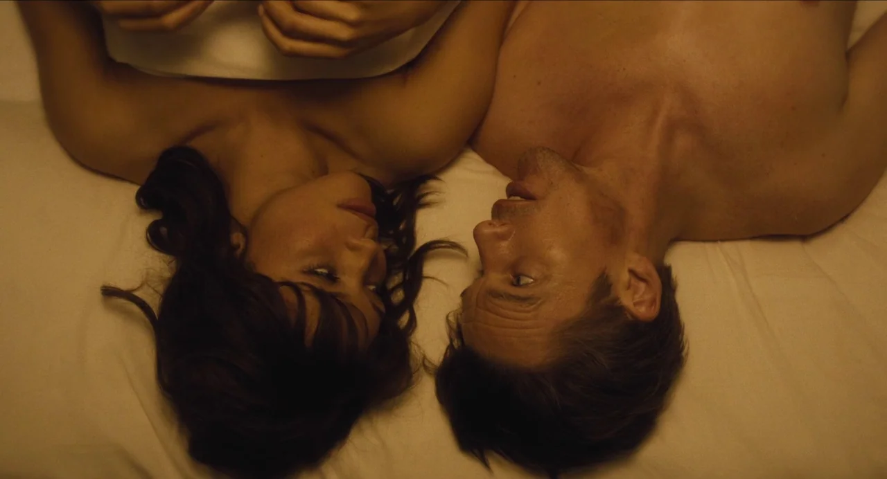 Born To Be Blue (2015) movie still: medium — A top-down view of a man and woman lying together on a white sheet. They are positioned parallel to one…