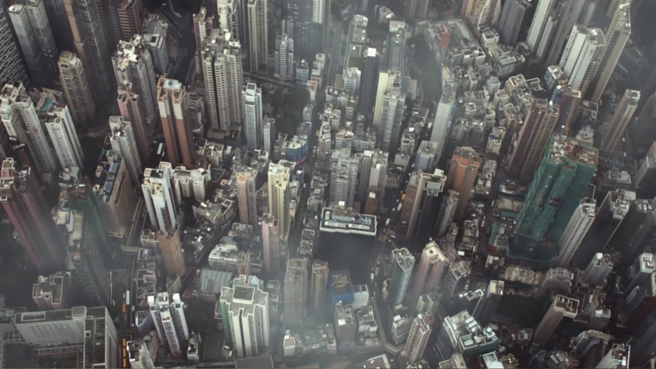 Skyscraper (2018) movie still: establishing — A dense urban environment shows numerous high-rise apartment buildings clustered closely together. The…