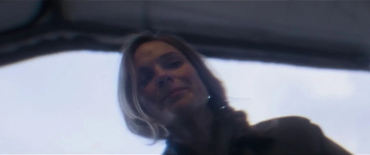 Mission: Impossible – Fallout (2018) movie still: closeup — A woman looks down from an overhead perspective inside a vehicle cabin. The background…