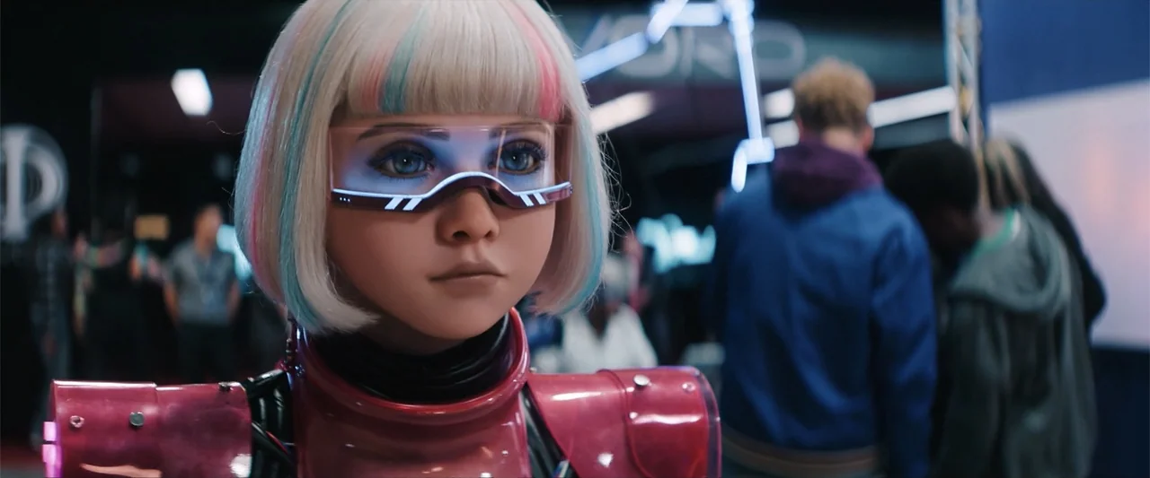 M3GAN 2.0 (2025) movie still: closeup — A crowded hall filled with indistinct figures and tech equipment. A young character with colored hair and a…