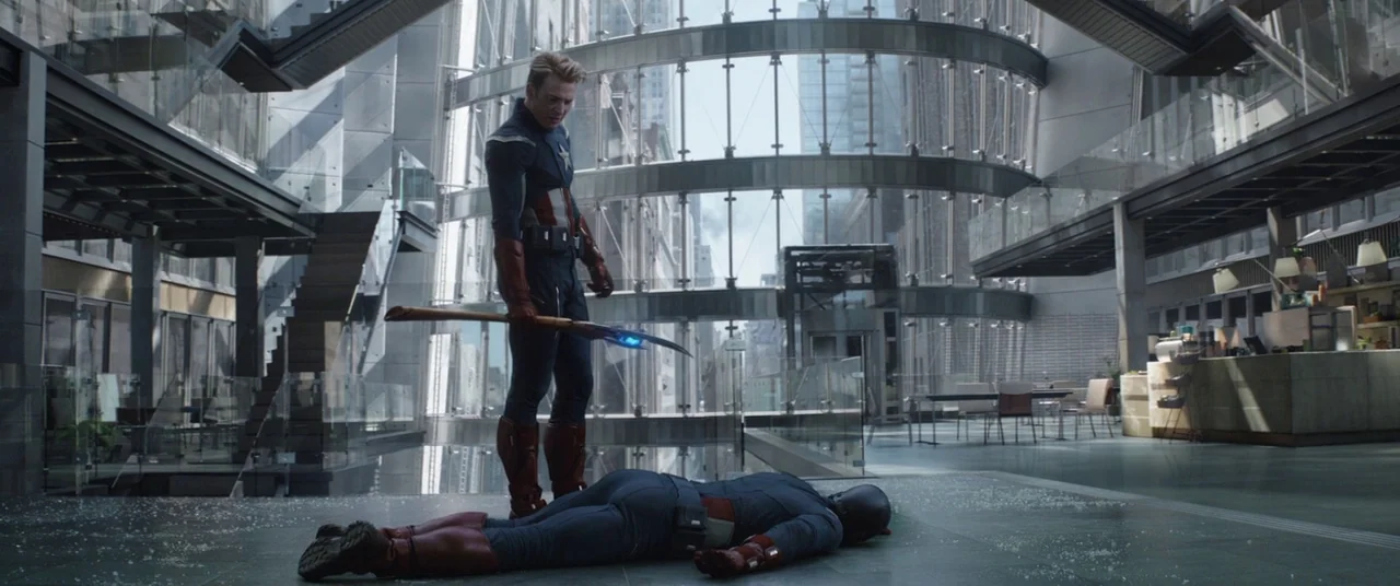Avengers: Endgame (2019) movie still: wide — A spacious, modern corporate lobby with glass walls and dark steel staircases. One man in a tactical…