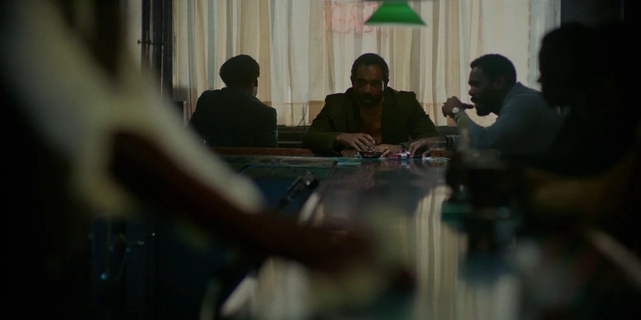 If Beale Street Could Talk (2018) movie still: medium — A dimly lit bar with a long counter and window curtains in the background. Several men sit…
