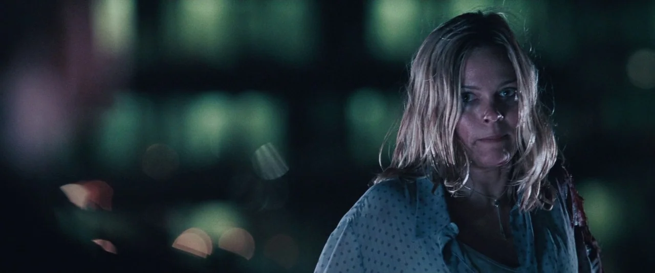 Resident Evil: Apocalypse (2004) movie still: medium — A dark night street setting with blurred city lights forming deep green bokeh patterns. A…