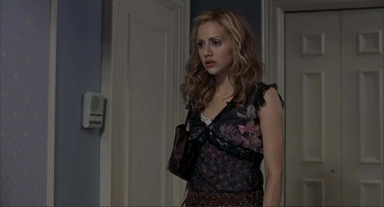 Uptown Girls (2003) movie still: medium — A residential interior hallway features light blue walls and two closed white doors. A woman stands in the…