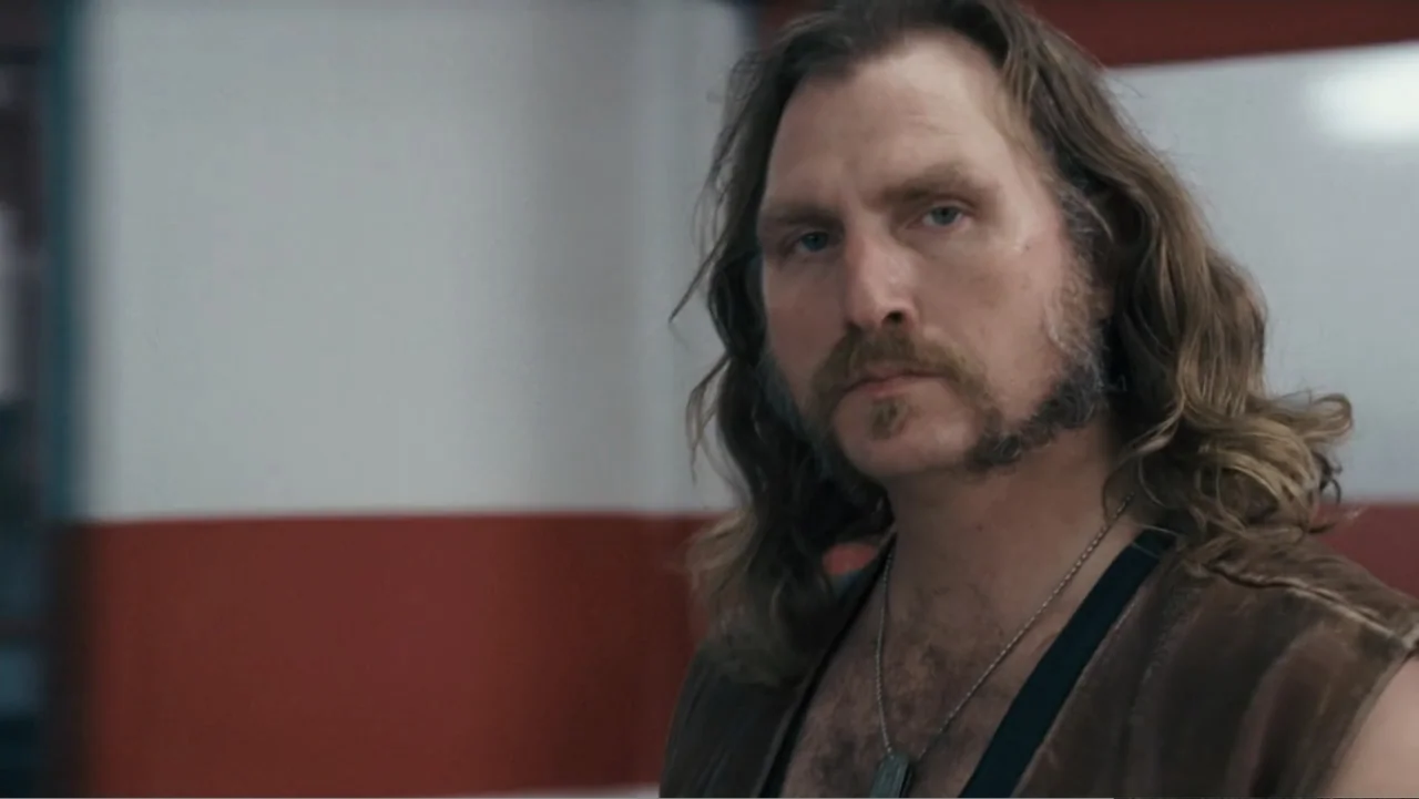 Fun with Dick and Jane (2005) movie still: medium — A man stands in front of a white and red wall in an interior space. The subject looks directly…