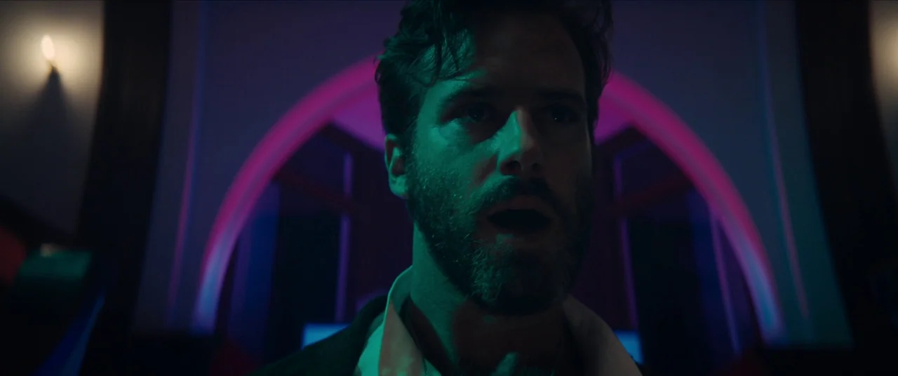 Sorry to Bother You (2018) movie still: closeup — A man stands in a dark corridor framed by a glowing neon archway. He looks forward with his mouth…