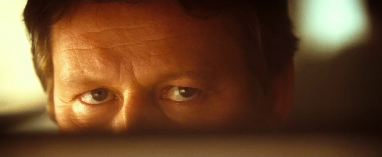 Trick ‘R Treat (2007) movie still: closeup — A dark indoor space with a man's eyes visible in the lower center. The man stares directly forward…
