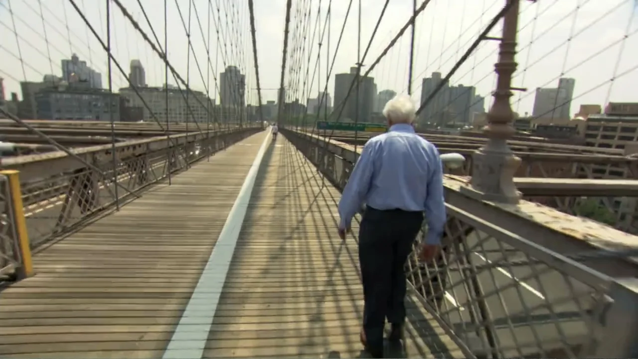 David McCullough: Painting with Words (2008) movie still: fullbody — A wooden pedestrian walkway on a large suspension bridge with metal cables…