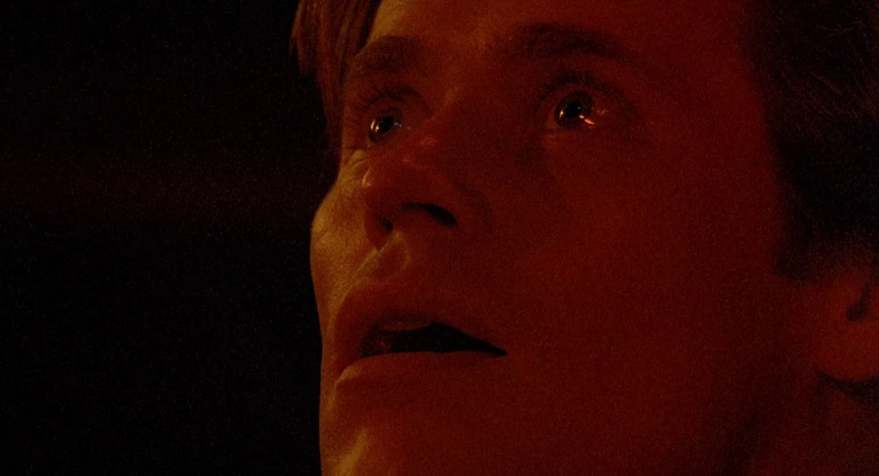 To Live and Die in L.A. (1985) movie still: closeup — A man's face is illuminated from below against a pitch-black background. He looks upward with…