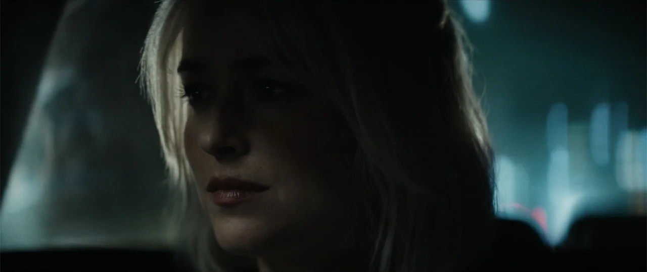 Daddio (2024) movie still: closeup — The interior of a vehicle is dark with blurred city lights visible outside. A woman sits motionless in the…